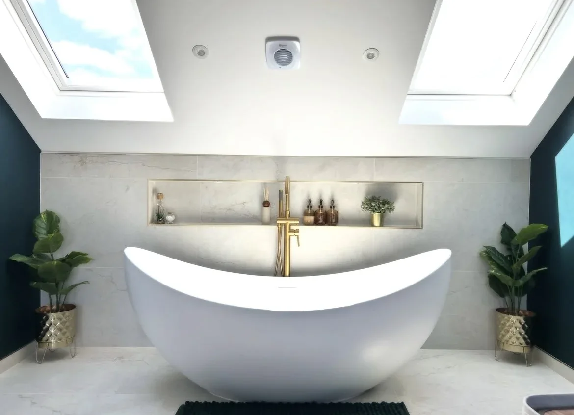 White freestanding bath beneath two rooflights and a tiled wall.