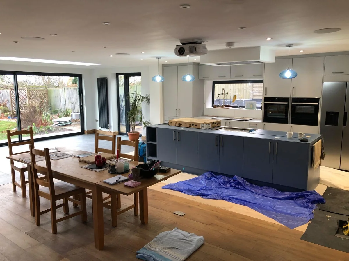 Grey kitchen island and dining table in an open room with garden glazing.