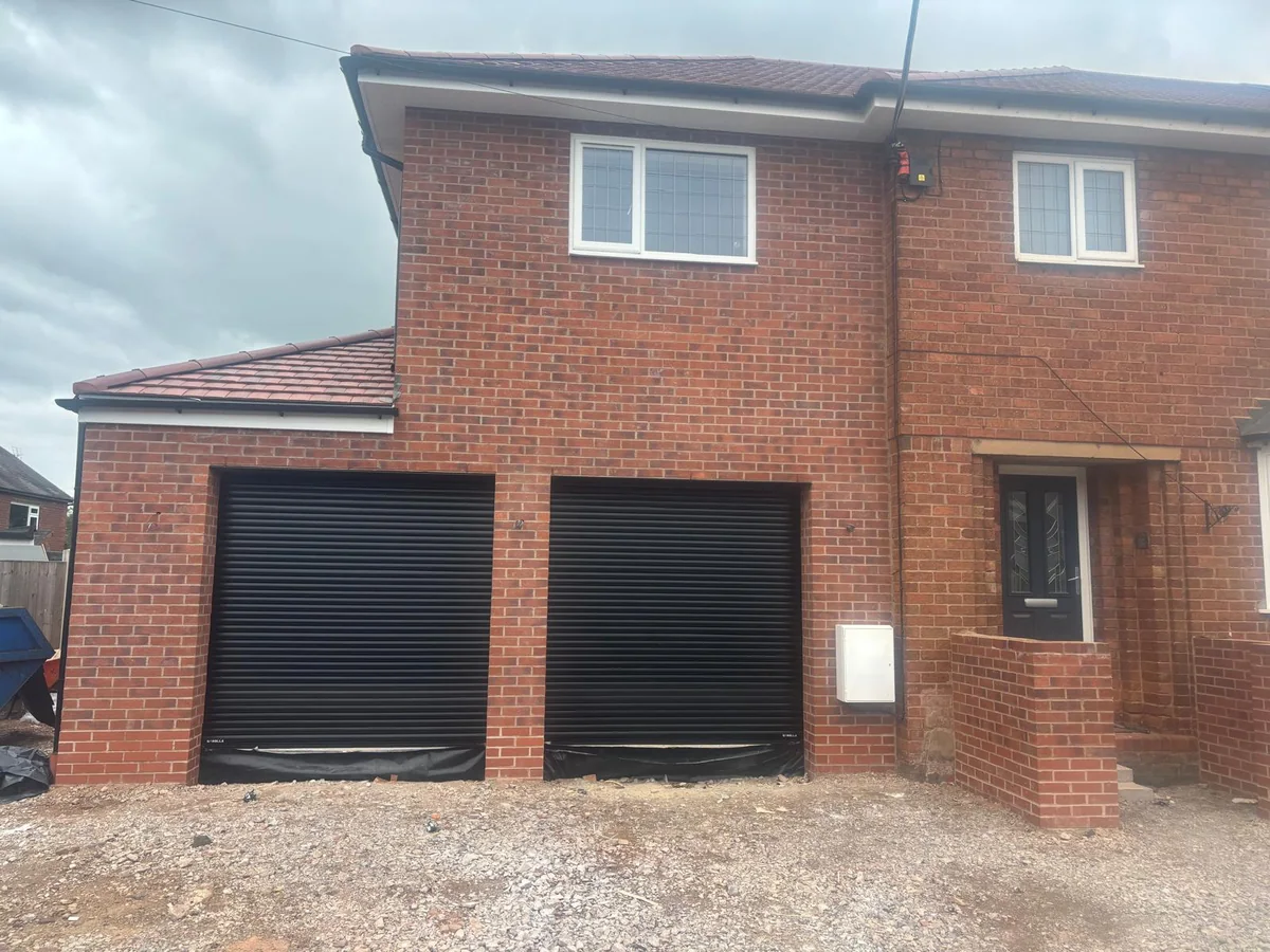 Two dark garage shutters on a brick house