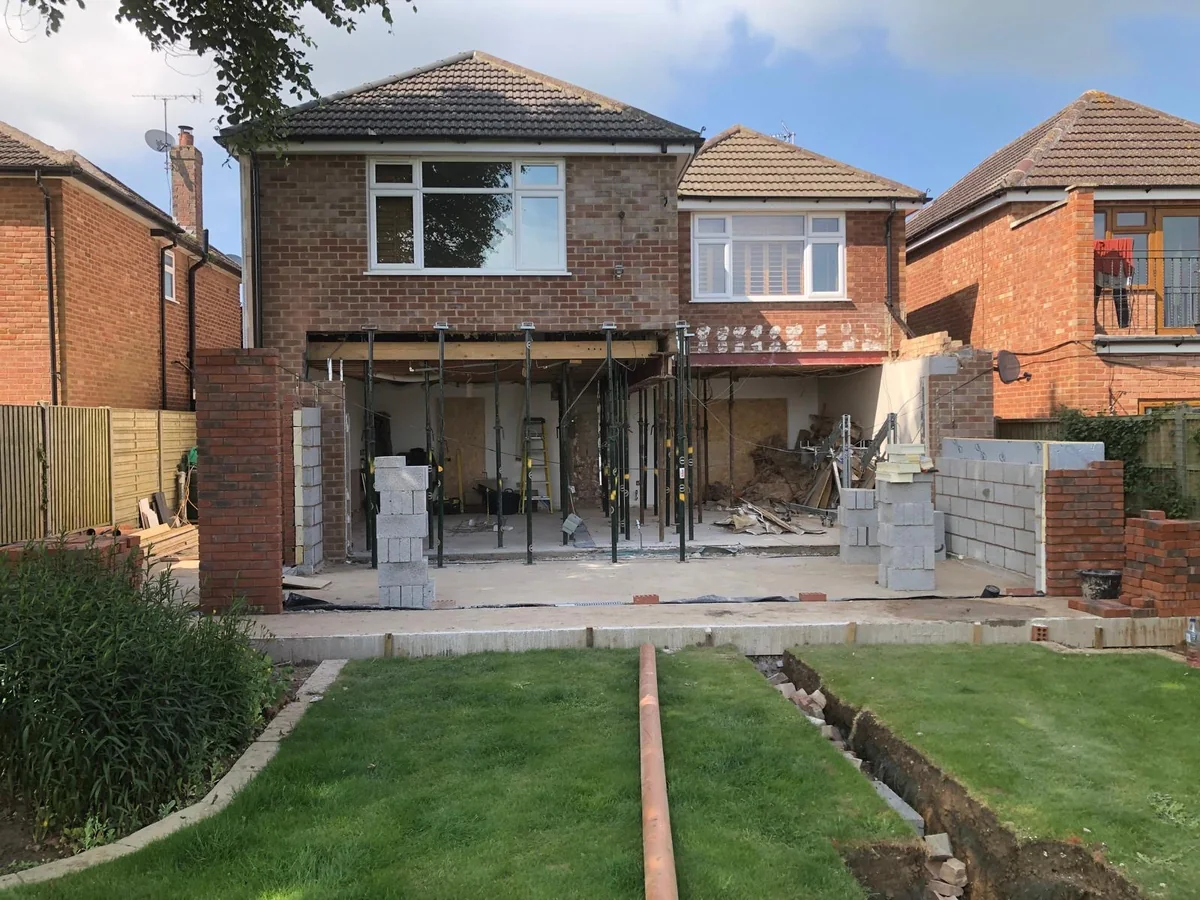 Brickwork and temporary supports beneath the rear of a two storey house.