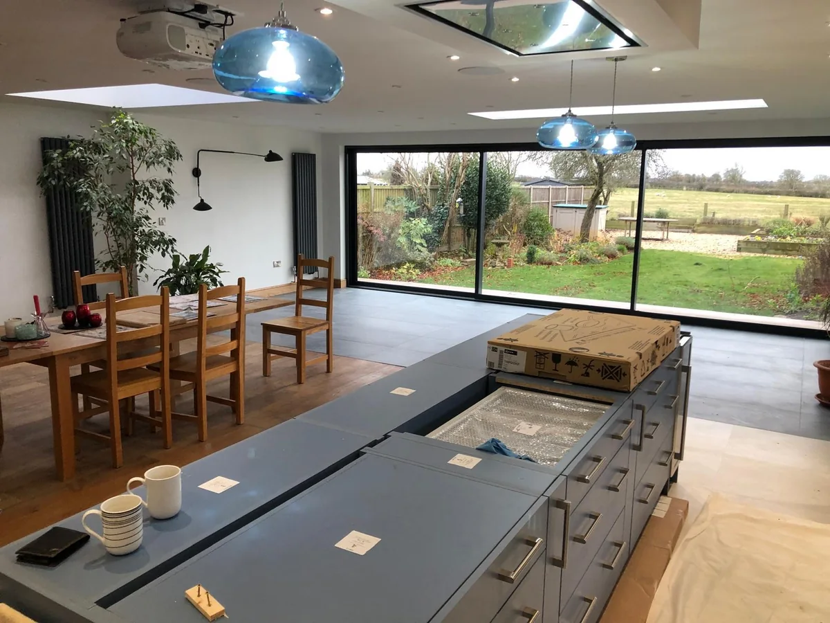 Finished kitchen island beneath pendant lights facing wide garden doors
