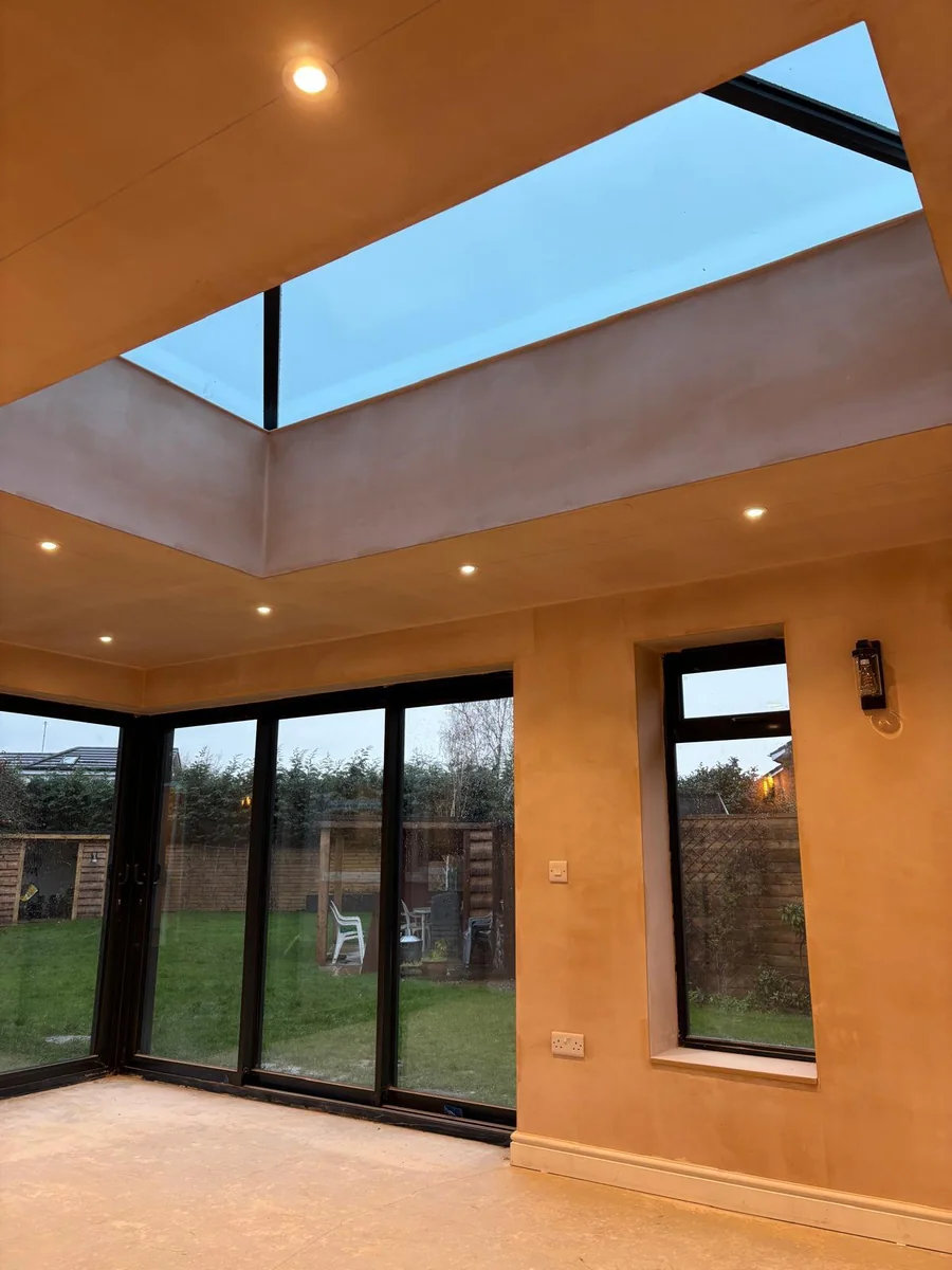 Roof lantern above a room with black framed garden doors and unfinished flooring.