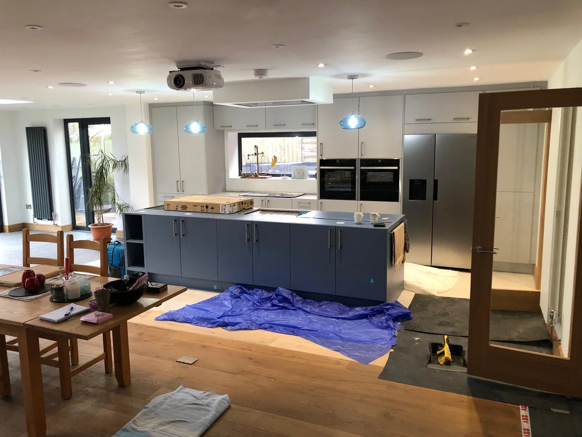 Kitchen island, protected flooring and dining table during fitting.
