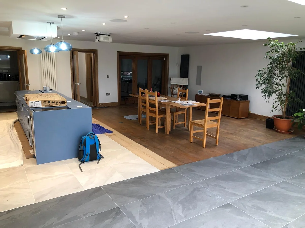 Grey kitchen island, dining table and wide garden glazing in an open room
