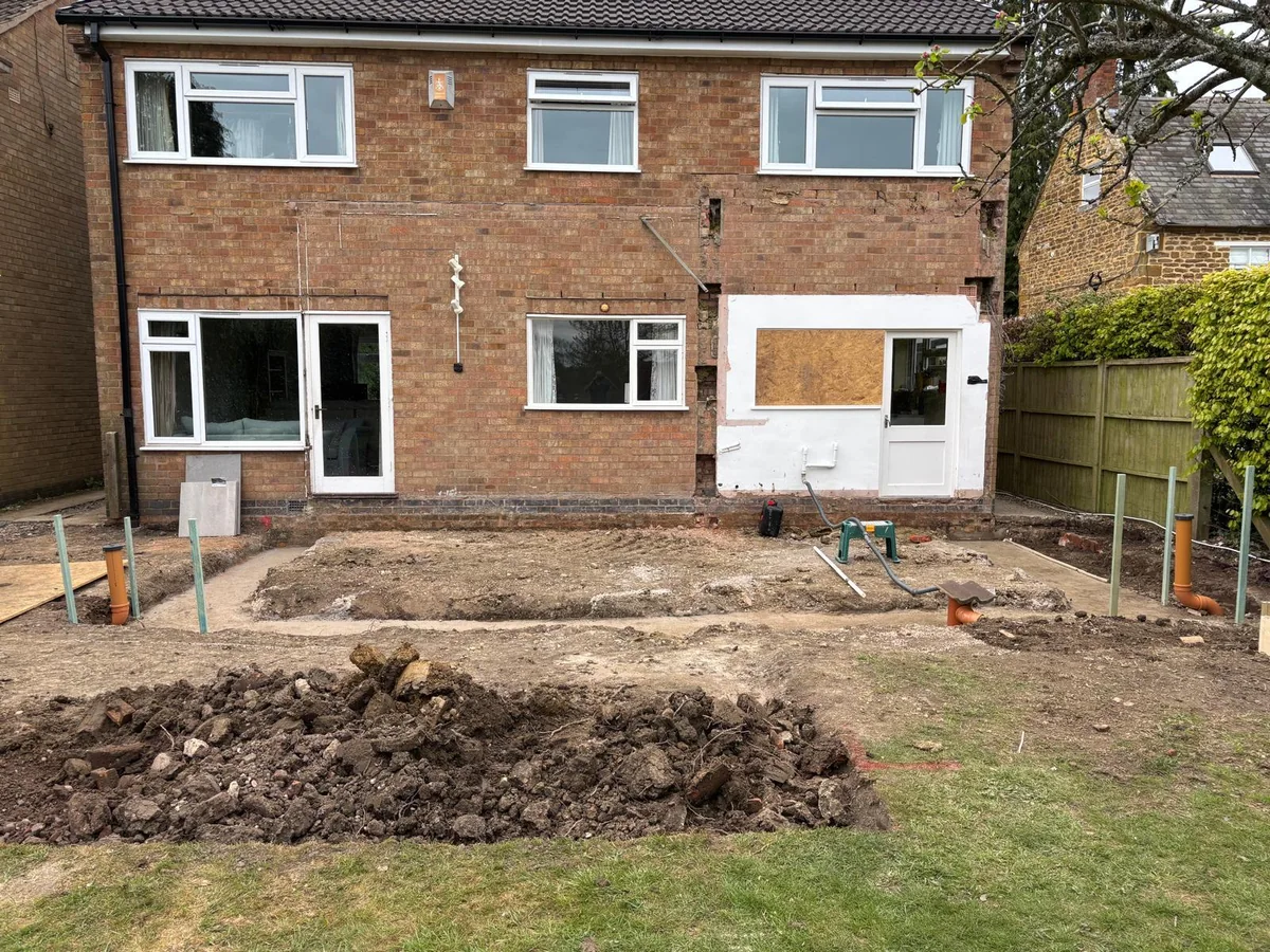 Prepared ground behind a brick house with service pipes and marked positions.