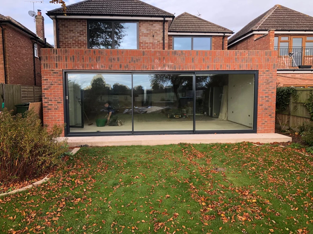 Brick rear extension with a wide glazed opening facing a lawn on a Belmax project
