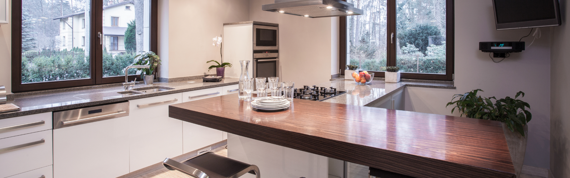 White kitchen with fitted appliances, stone worktops and a timber breakfast bar